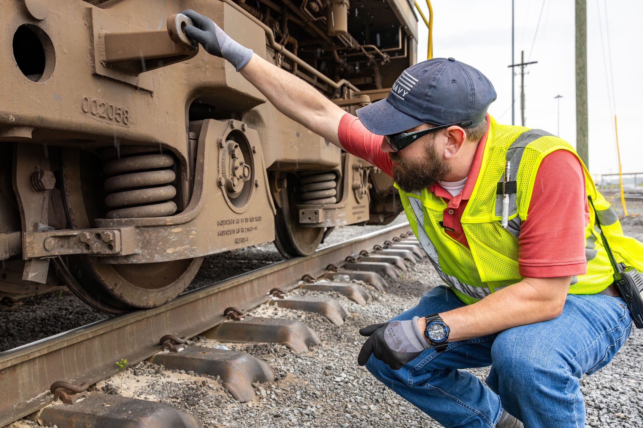 Man in safety vest squatting down looking at the base of a train helping their customer centric strateg