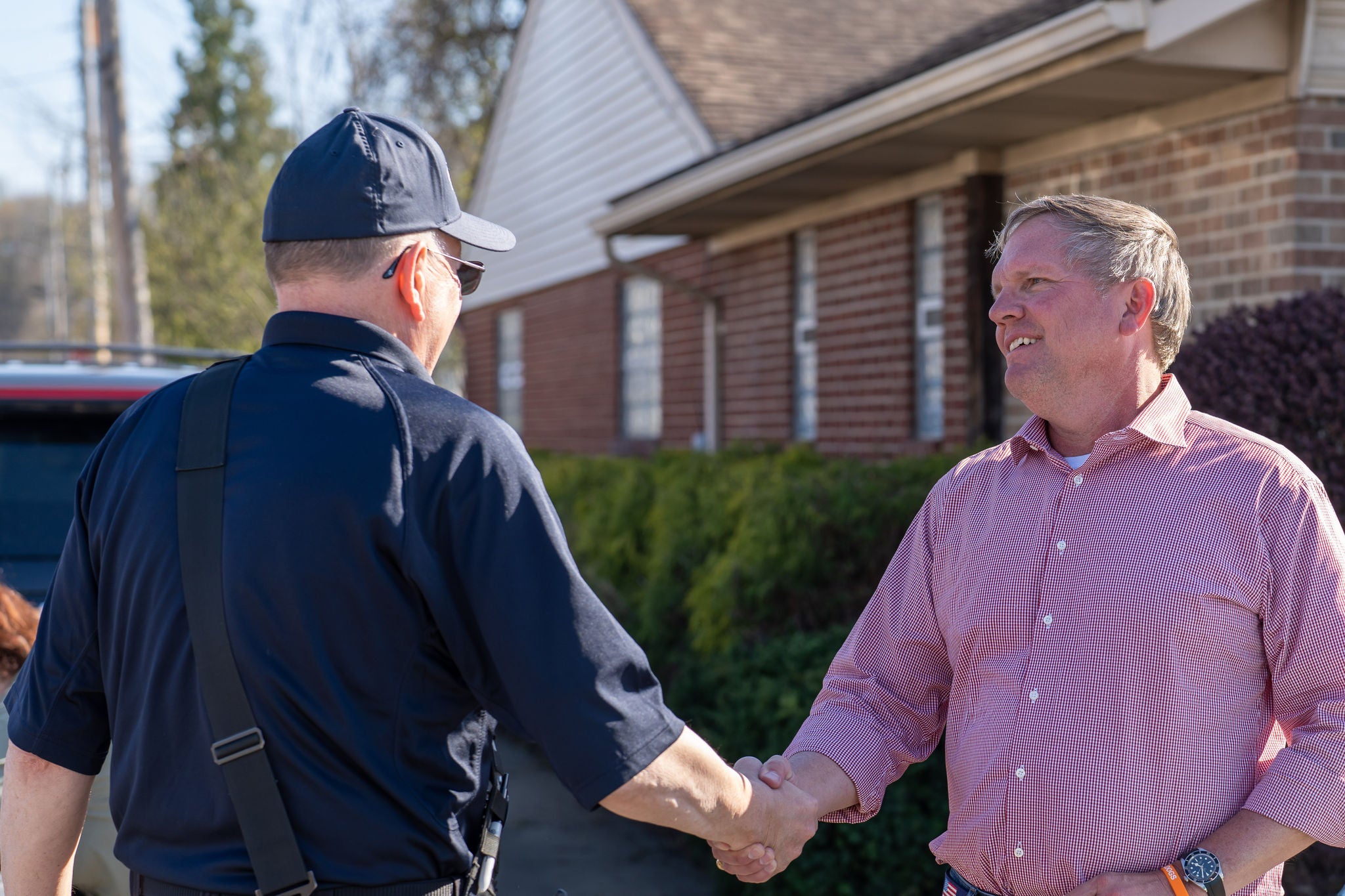 Community Support Alan shakes someone's hand in front of a brick building